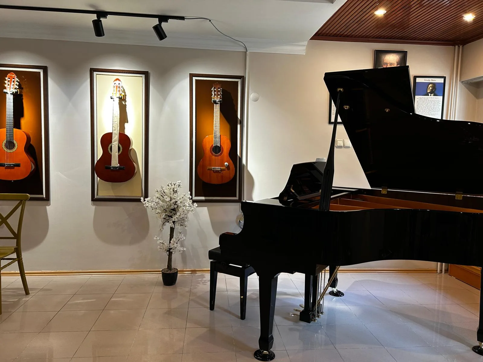 Anıl Akiş Akademi piyano sınıfında kuyruklu piyano ve duvarda gitarlar